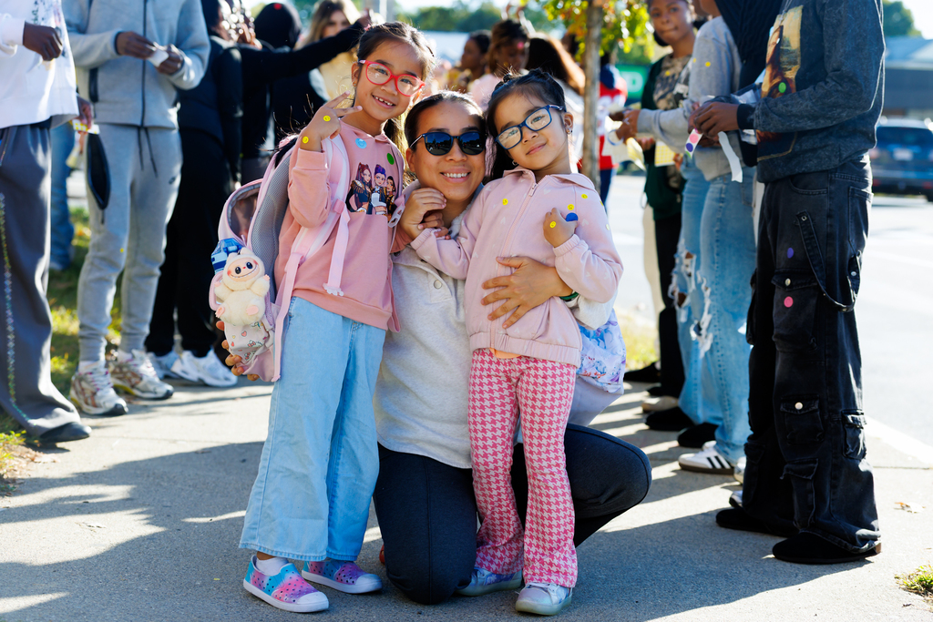A family of three smile and pose together for a photo.