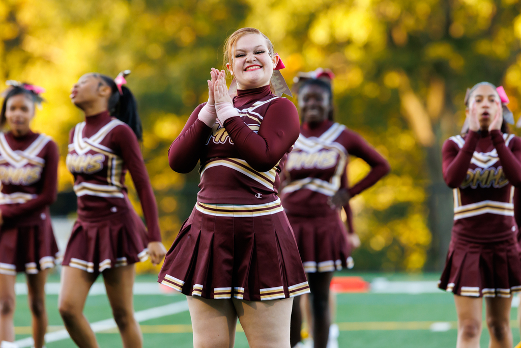 A cheerleader smiles and cheers after a performance.