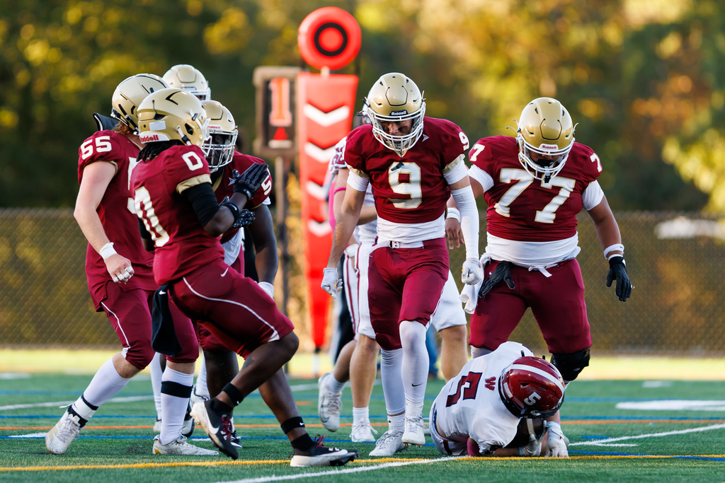A player yells following a tackle as his teammates surround him.