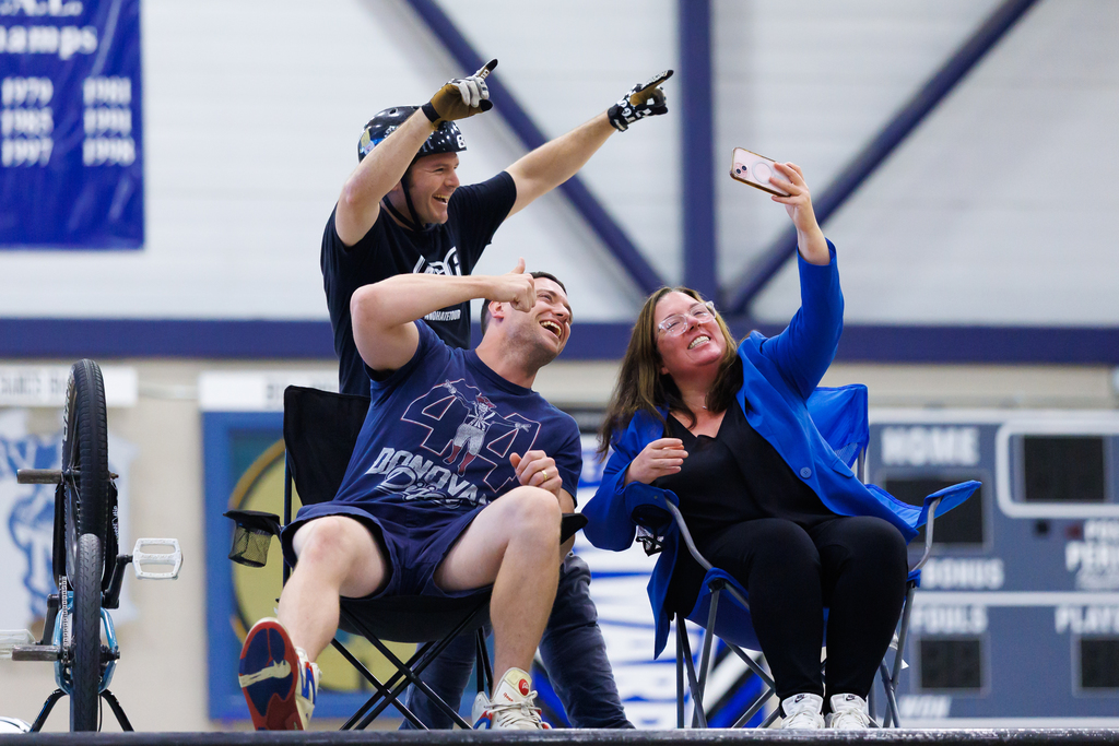 Two staff members from Worcester Tech take a photo with a BMX rider.