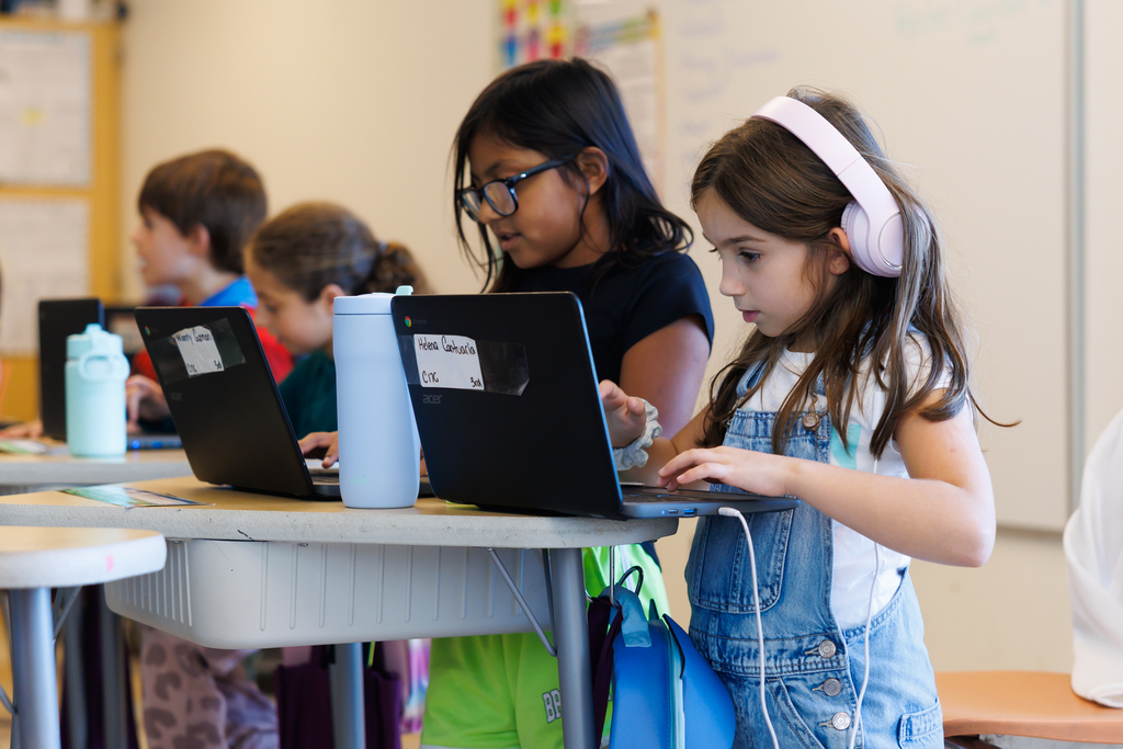 A group of students complete work on their laptops.