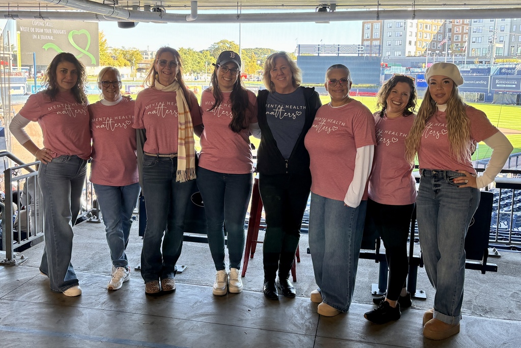 A group of women stand together, wearing matching 'Mental Health Matters' shirts.