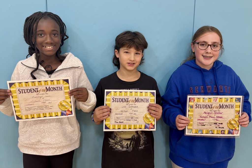 Three students proudly display their 'Student of the Month' certificates.