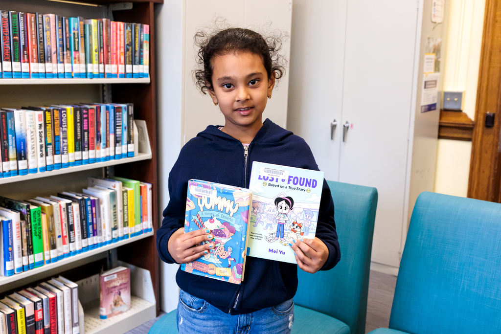 A Woodland Academy student holds up their book selections at the library.