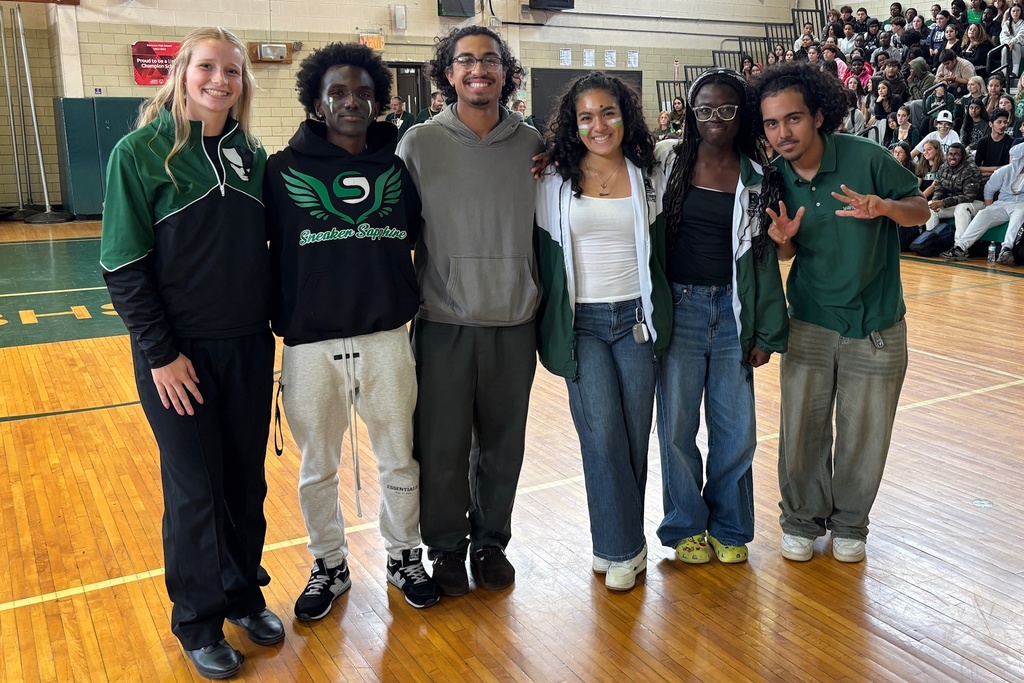 A group of students pose for a photo in a school gymnasium.