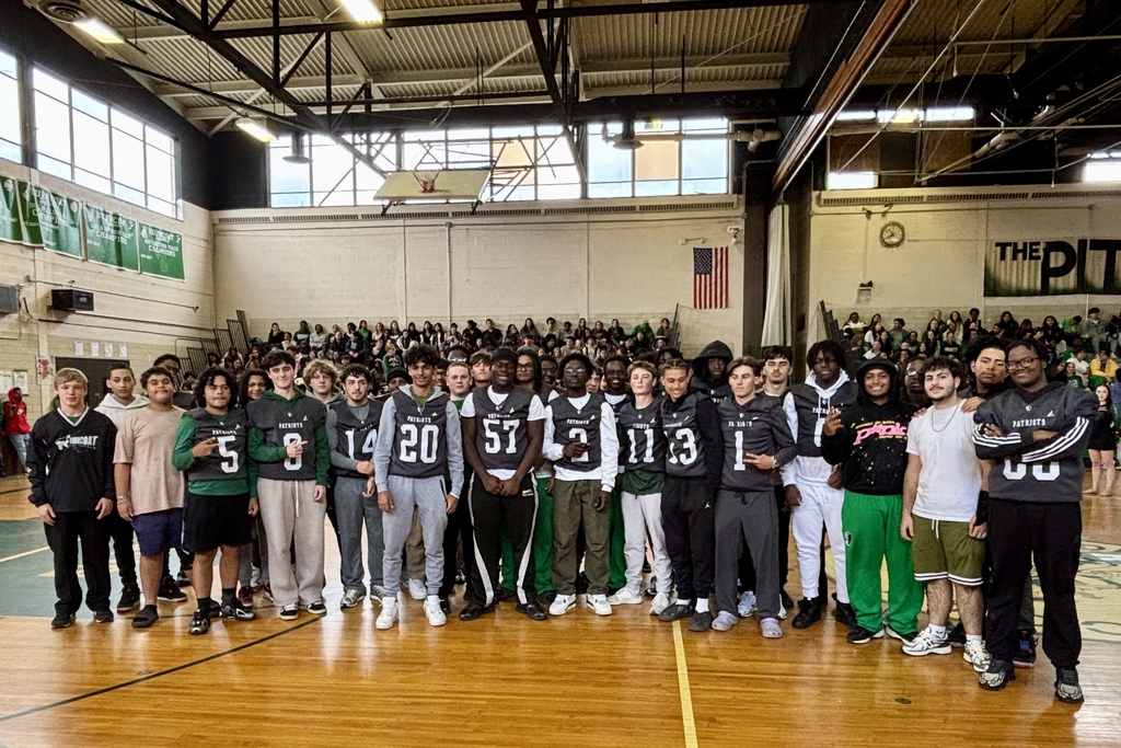 A group of young men, some in athletic jerseys, stand together in a gymnasium.