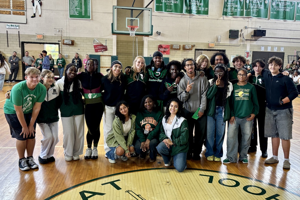 A diverse group of students pose together in a school gymnasium.