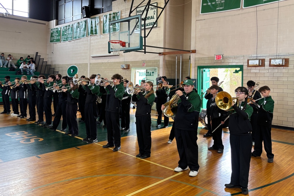 A school band practices in a gymnasium, holding brass instruments.