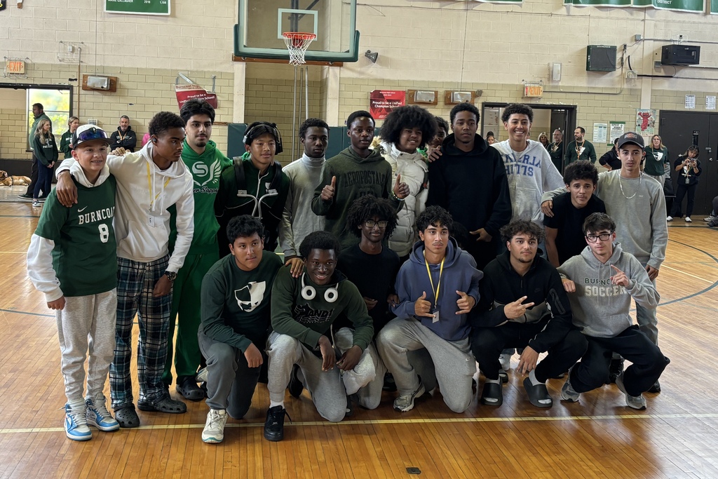 A diverse group of students pose together in a school gymnasium.