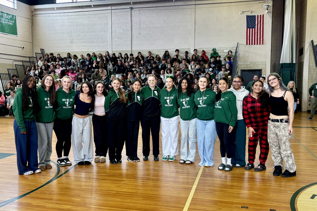A group of students pose for a photo in a school gymnasium.