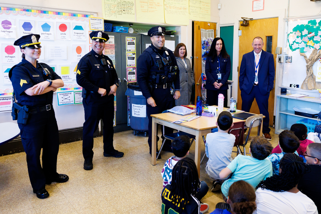 Police officers and school staff interact with students in a classroom setting.