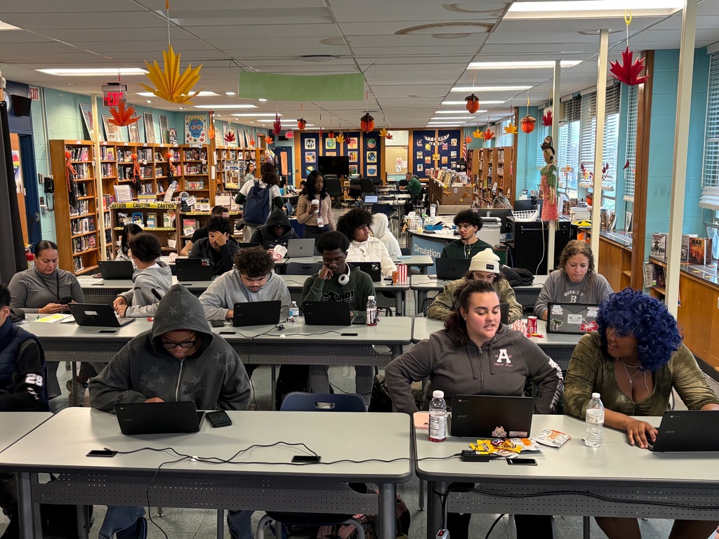A group of students and community members work on FAFSA applications during a school event.