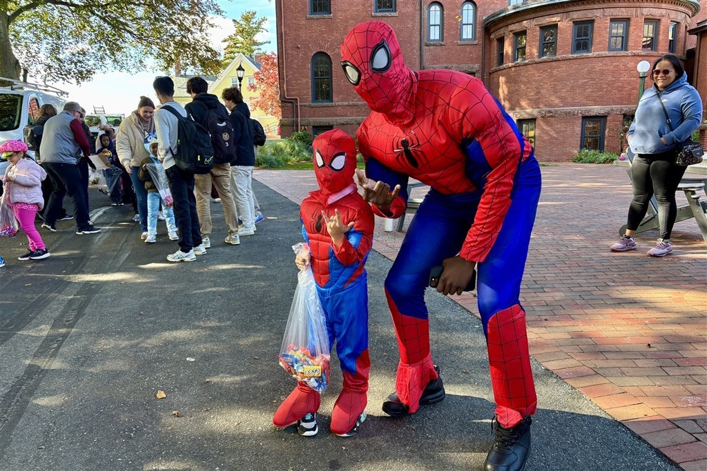Two people dressed as Spider-Man pose for a photo outdoors.