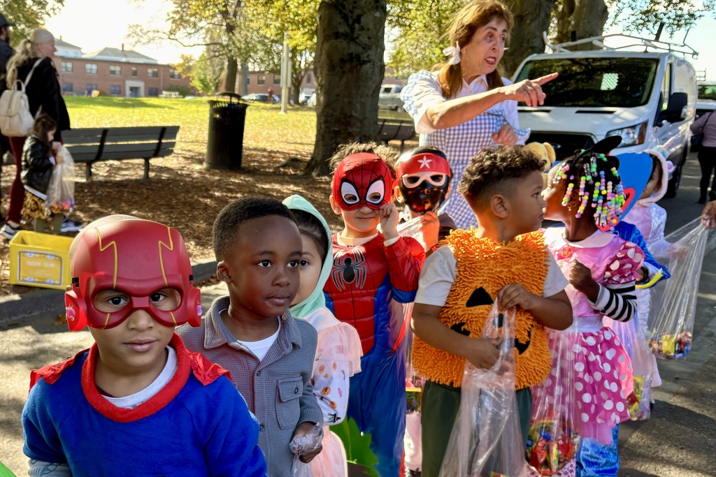 Children in costumes gather outdoors, possibly for a Halloween event.