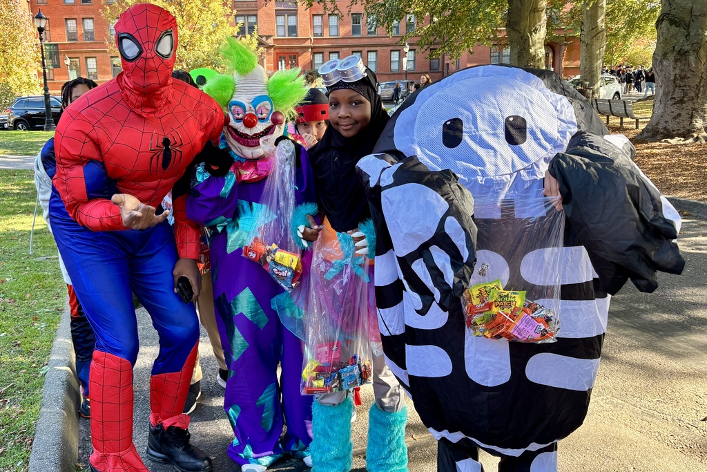A group of children in Halloween costumes pose for a photo outdoors.