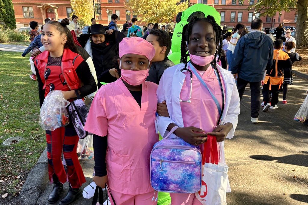 Children in Halloween costumes pose for a photo on a sunny day.