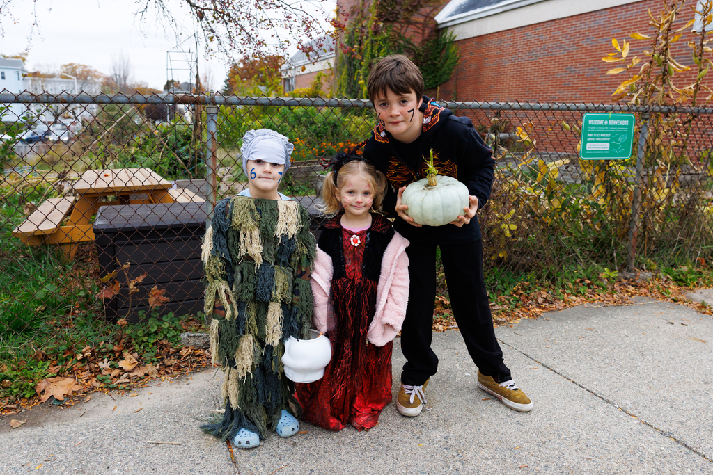Three students stand together for a photo while wearing Halloween costumes.