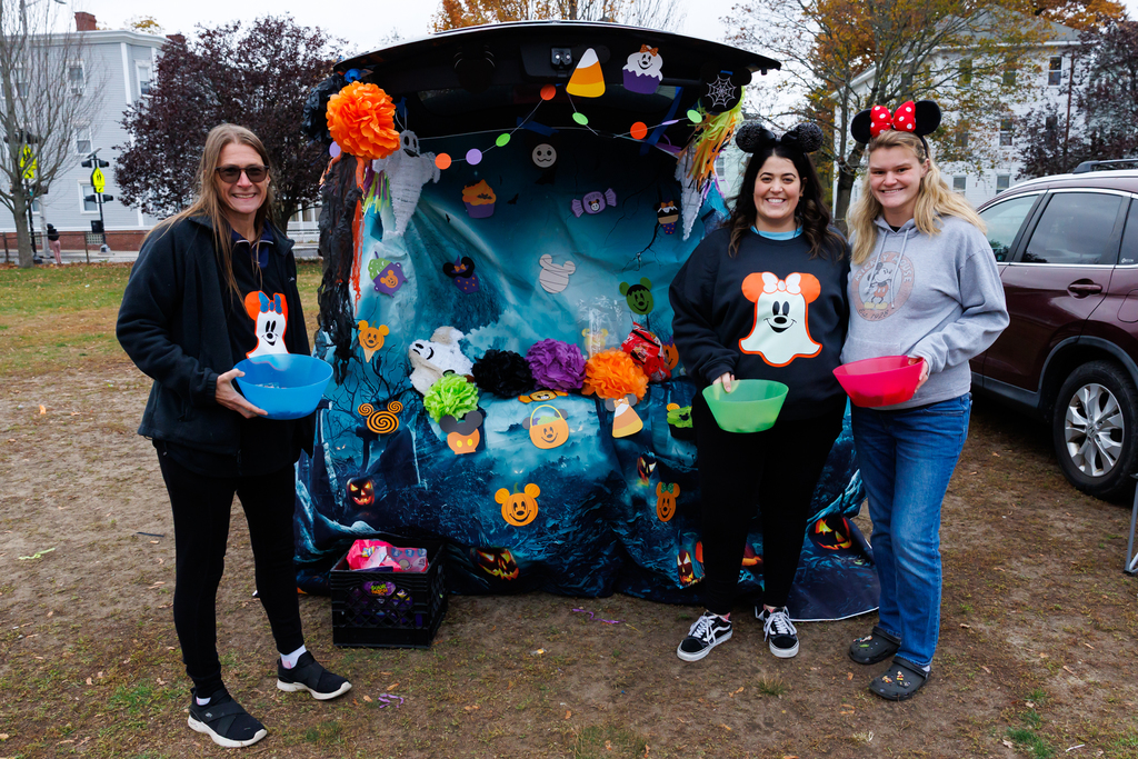 Three adults stand in front of their Disney themed Trunk or Treat display.