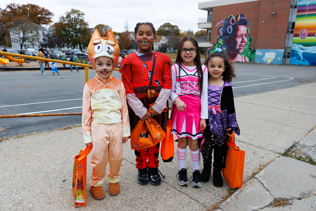 Four students stand together and smile while dressed in Halloween costumes.