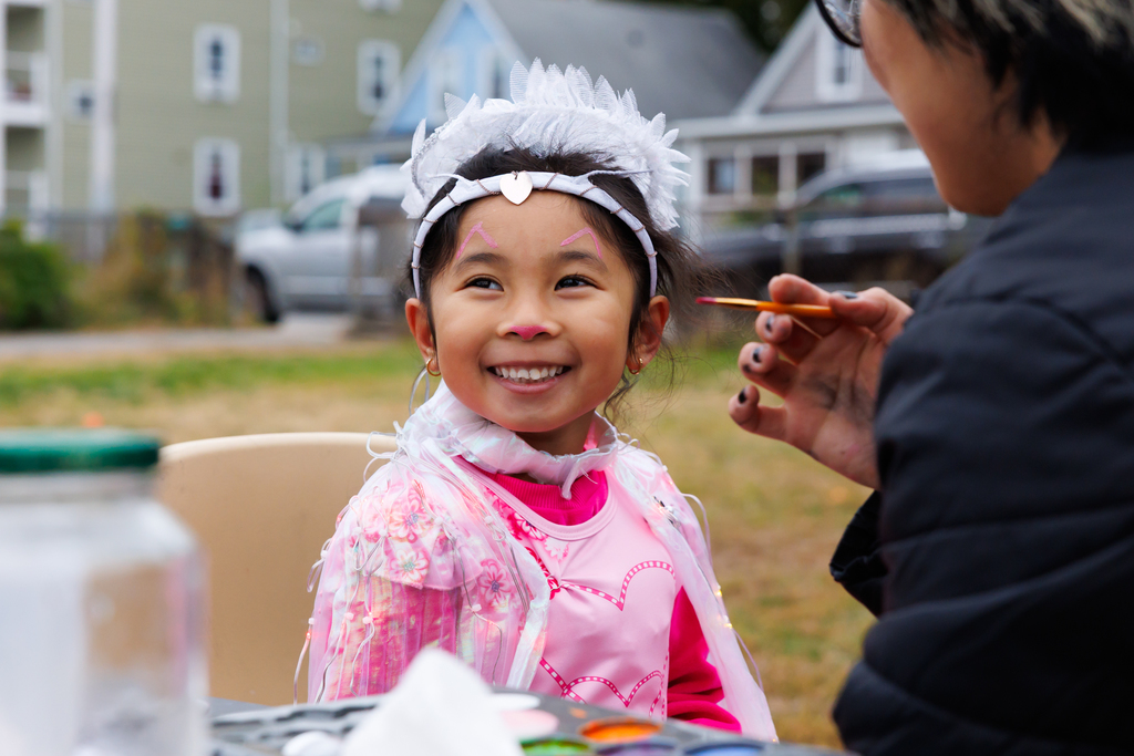 A student dressed as a princess smiles while getting their face painted.