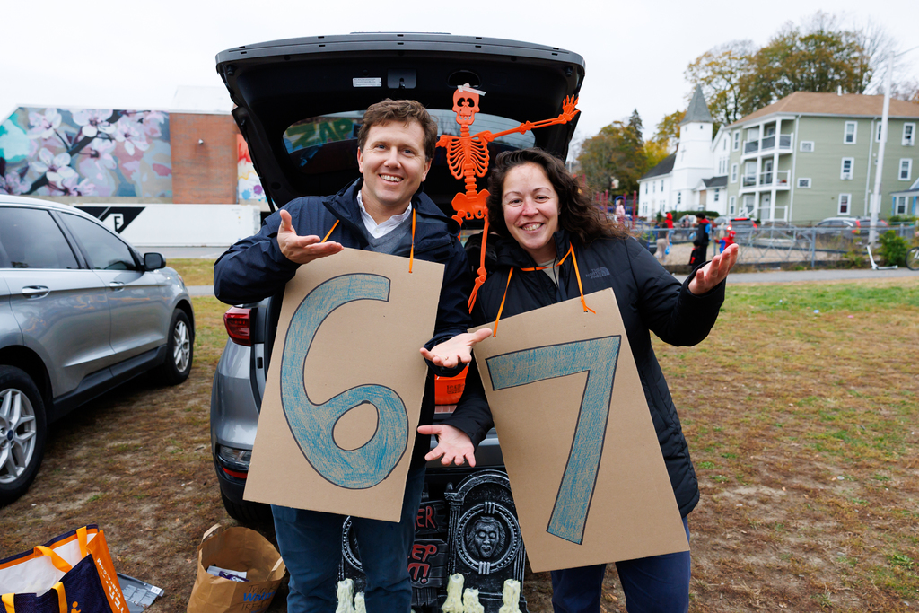 Two staff members stand for a photo while wearing a "6-7" Halloween costume.