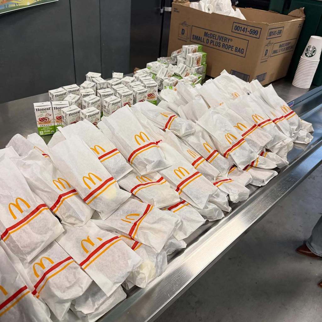 Many McDonald's wrapped sandwiches are arranged on a metal surface.