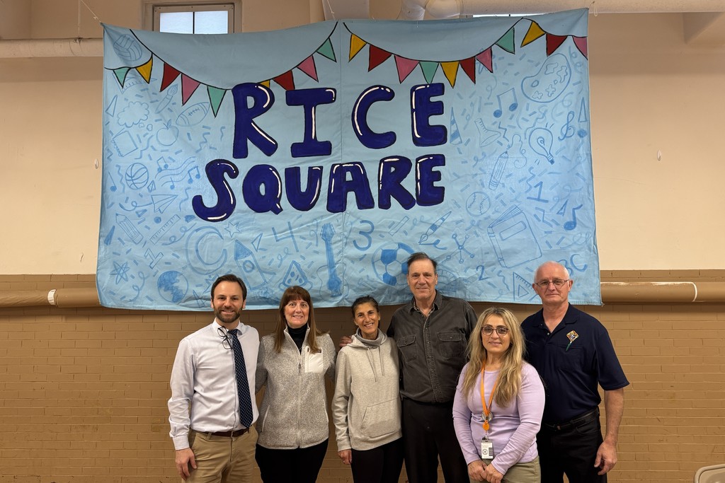 A group of six people pose in front of a banner that says 'Rice Square'.