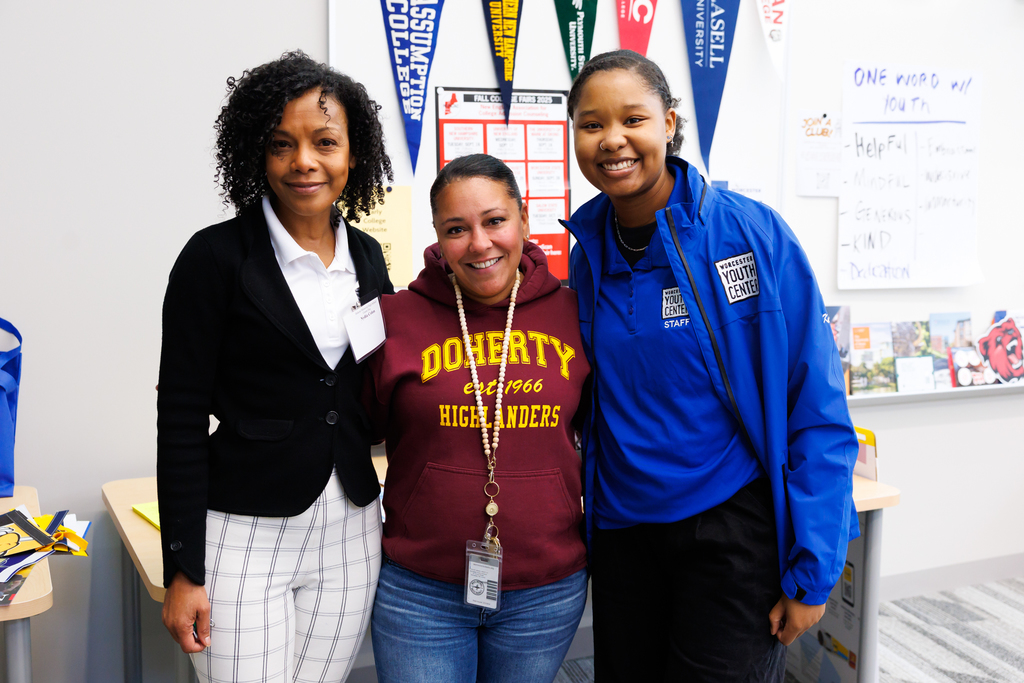 Three adults stand together for a photo.