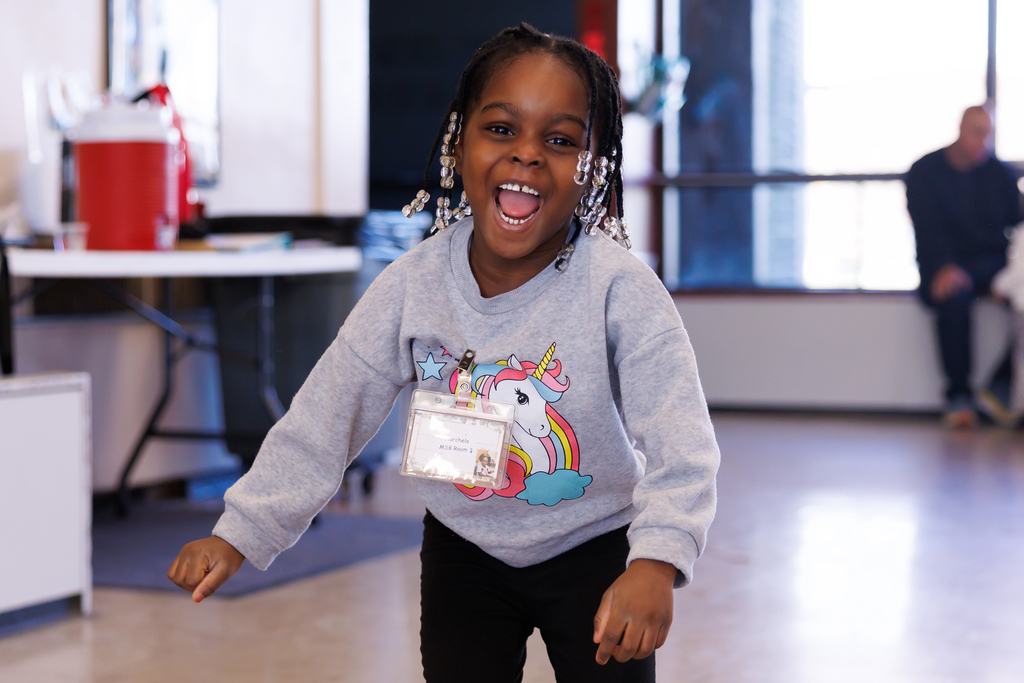 A pre-school aged student smiles while playing.