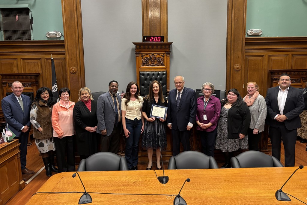 A group of people stand together in a formal room, posing for a photo.