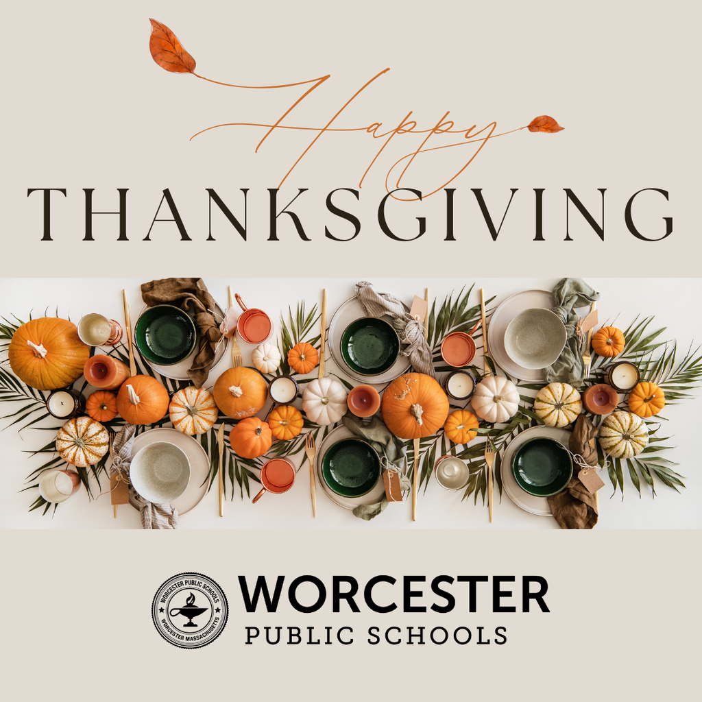 Thanksgiving table setting with pumpkins, plates, and greenery.