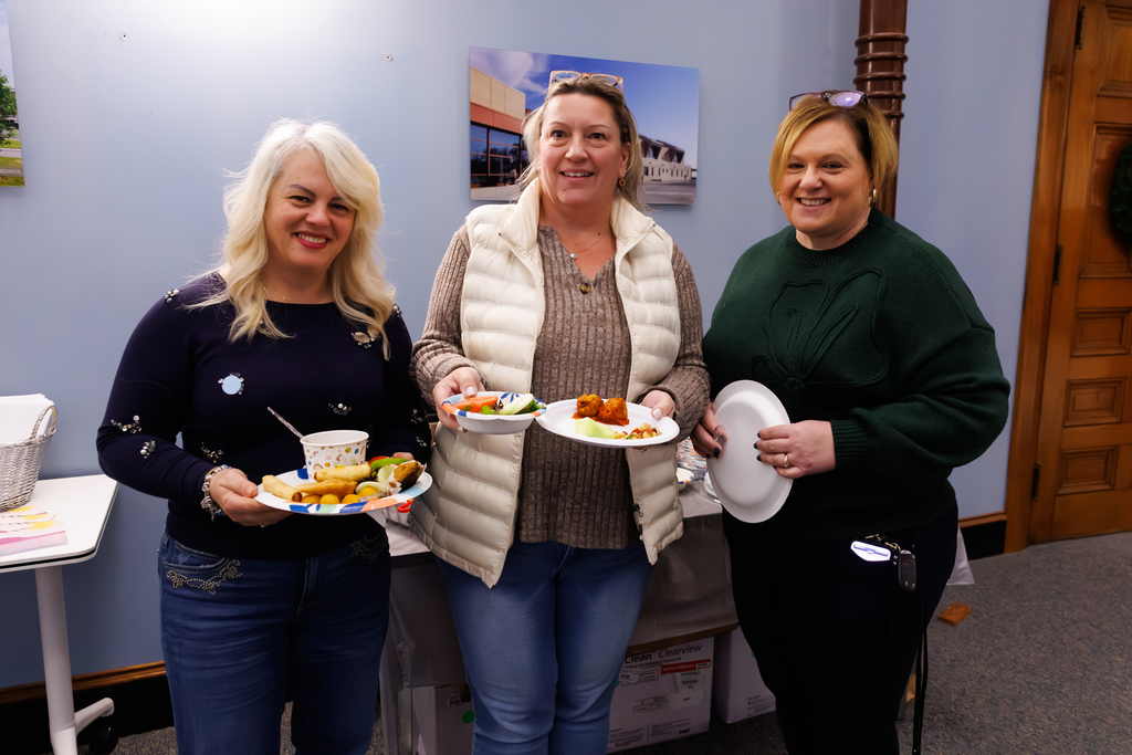 Three WPS colleagues stand together for a photo while holding plates during a staff lunch.