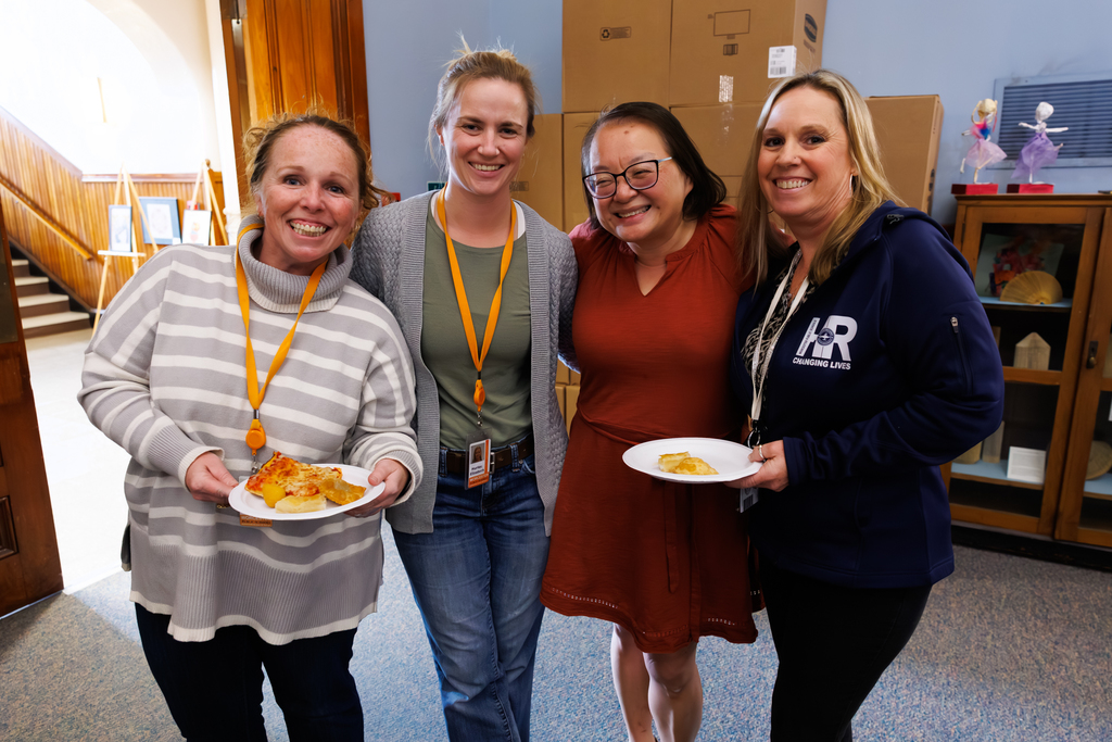 Four WPS colleagues stand together for a photo while holding plates during a staff lunch.