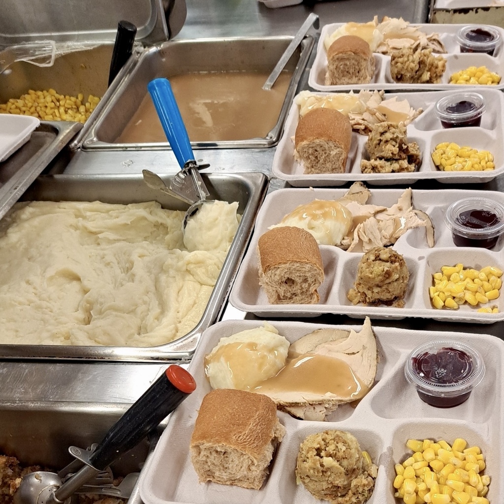 Prepared trays of food with turkey, mashed potatoes, and other sides.