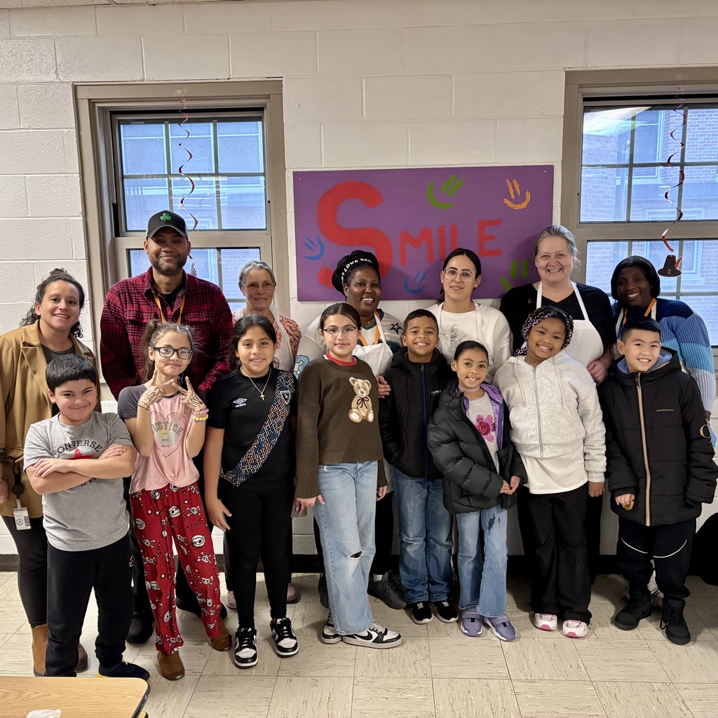 A diverse group of people, including children and adults, pose together indoors.