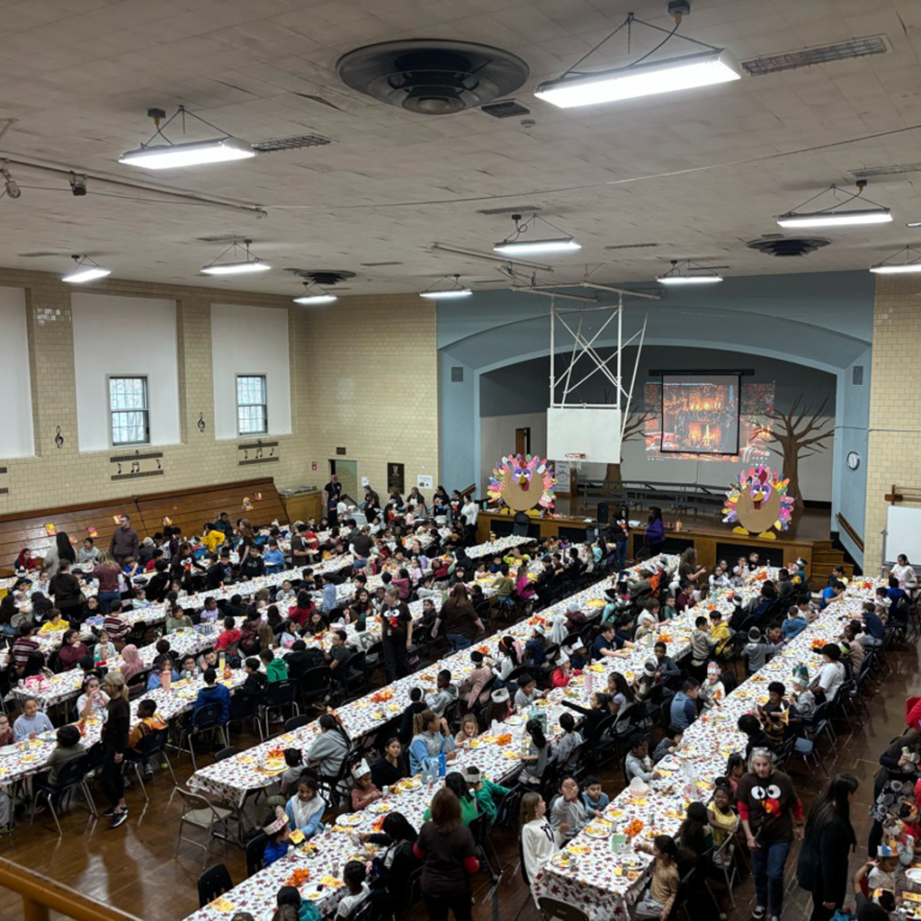 The gymnasium full of students and staff enjoying a meal together.