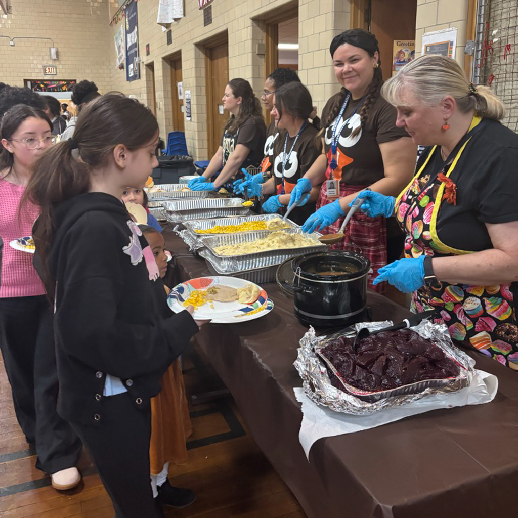 Staff members serve food to students.