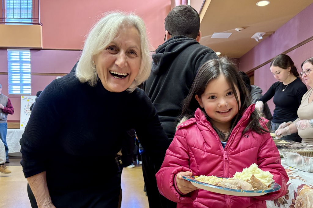 A smiling woman and a young girl pose for a photo at a community event.