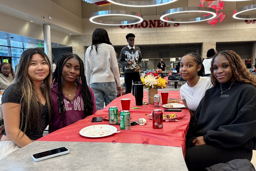 A group of young people sit around a table, smiling at the camera.