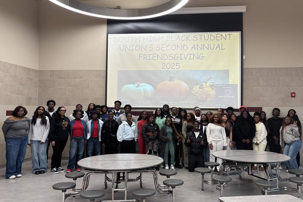 A large group of students pose for a photo in front of a Friendsgiving banner.