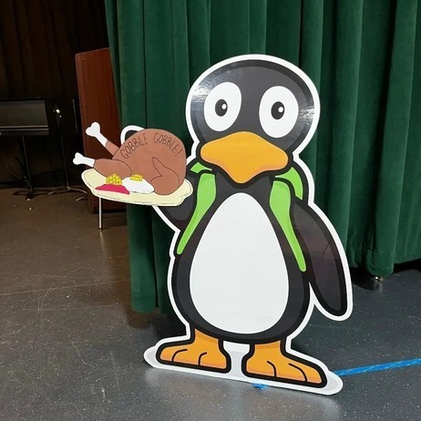 A penguin cutout holds a tray with a cartoon turkey, with 'GOBBLE GOBBLE!' written on it.