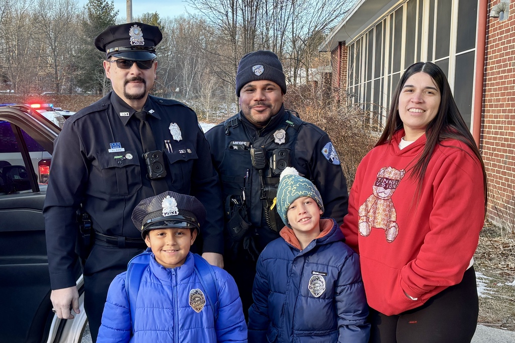 Two police officers pose with a woman and two children, smiling for the camera.