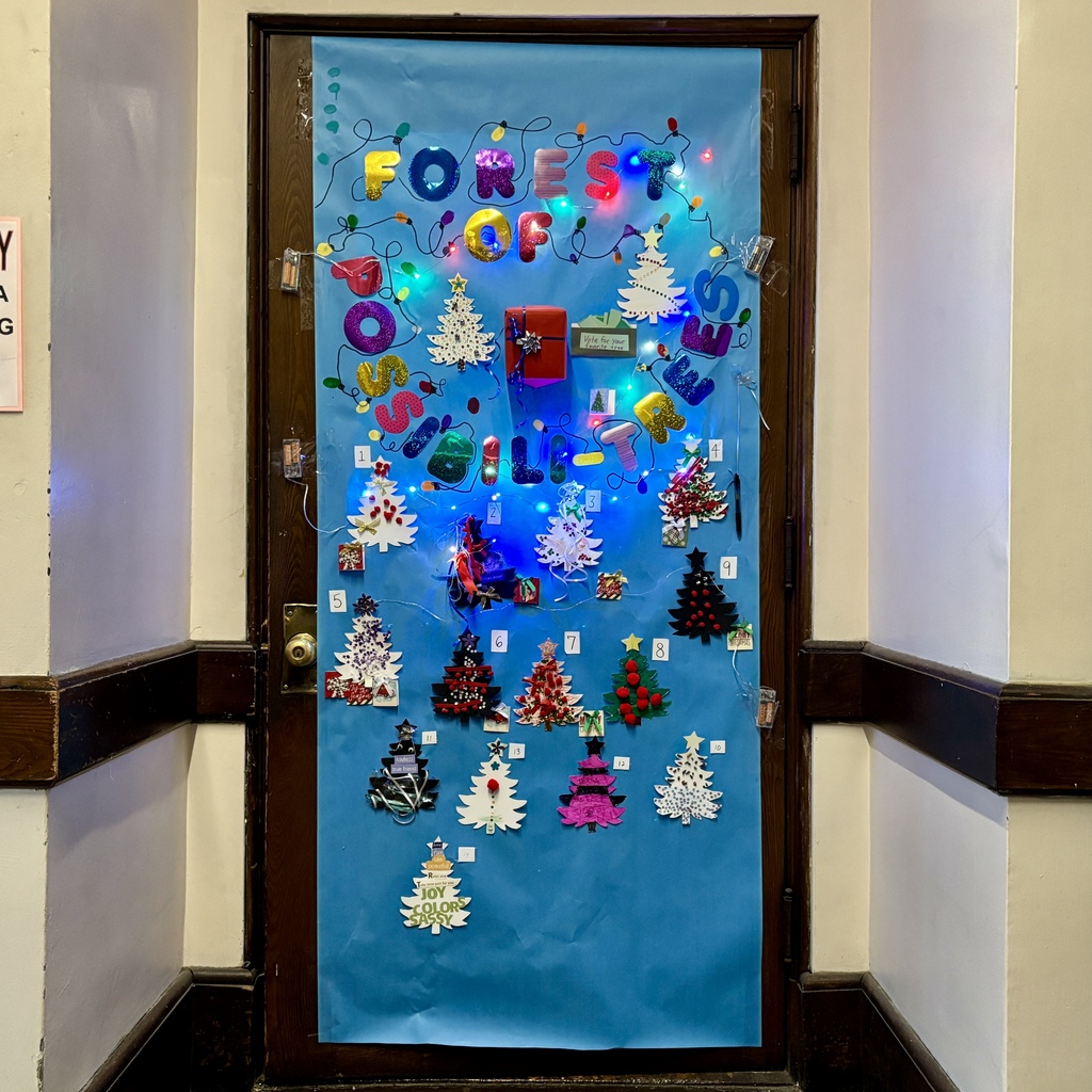 A decorated door displays the words 'FOREST OF TREES' with colorful letters and Christmas tree cutouts.