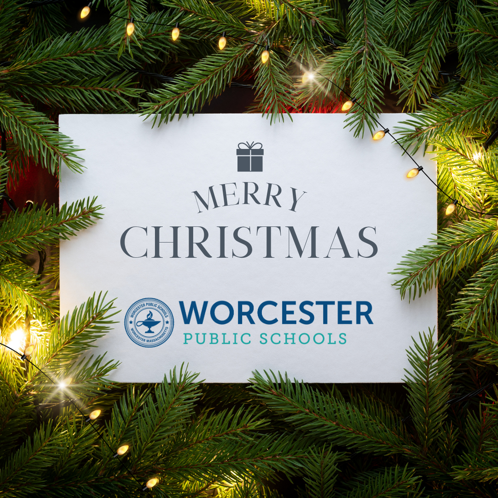 A white card with "Merry Christmas" and "Worcester Public Schools" text, framed by green fir branches and warm fairy lights.