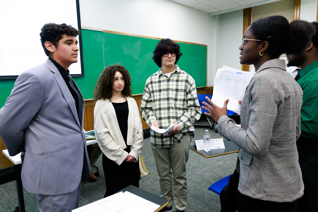 A student delegate debates with a group of three students representing a different country in a Model UN simulation.