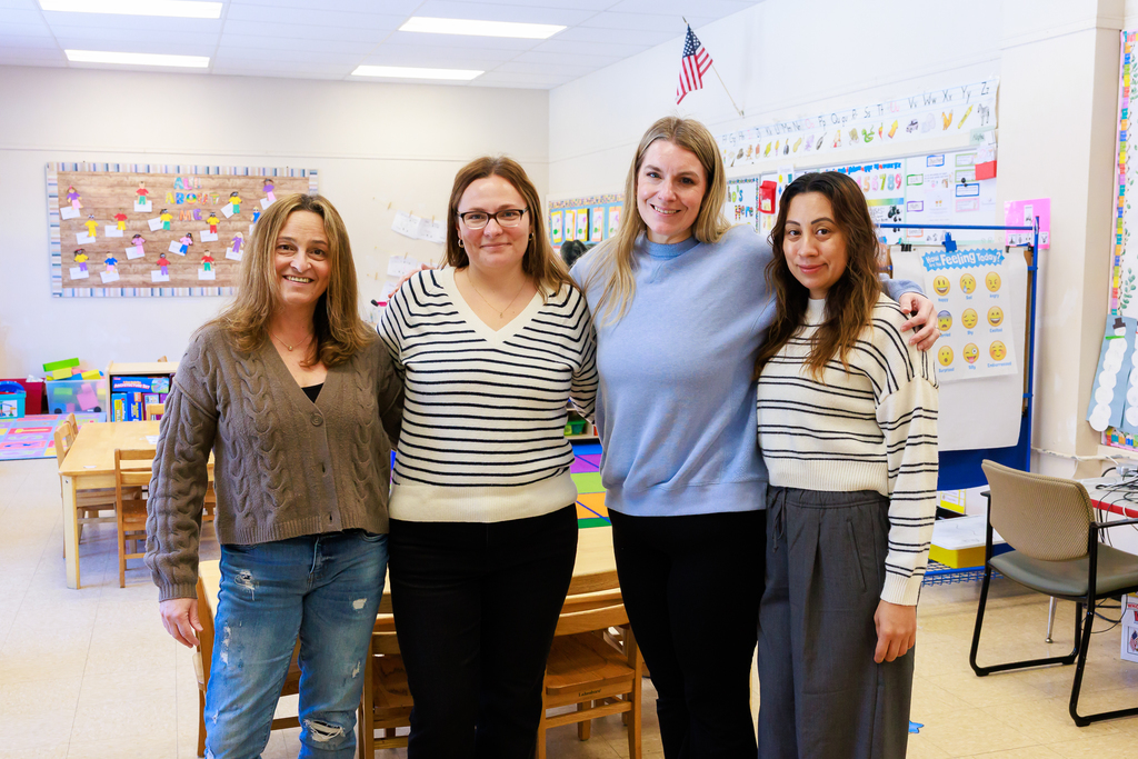 Four early education staff members stand together for a photo in an empty classroom.