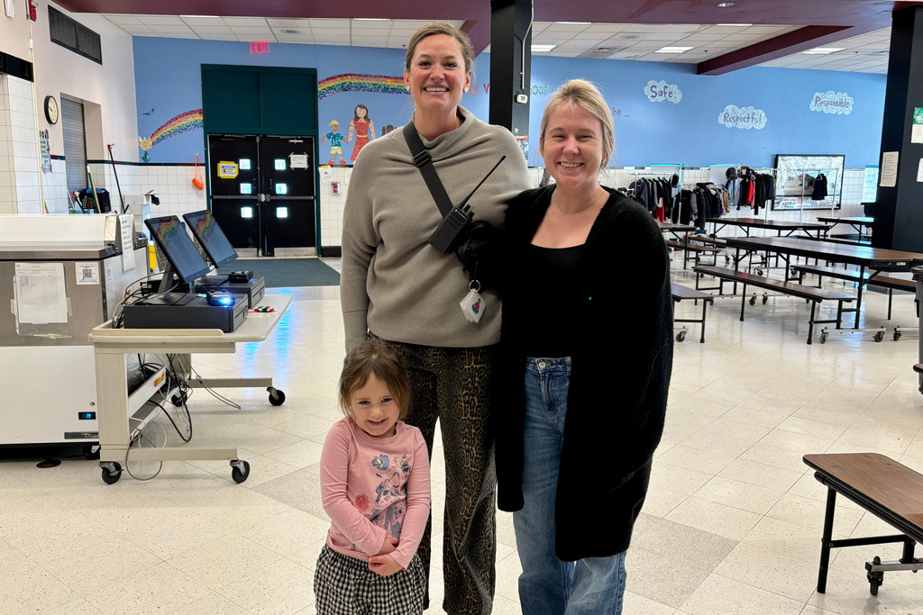 A young student and their mother stand with a staff member.
