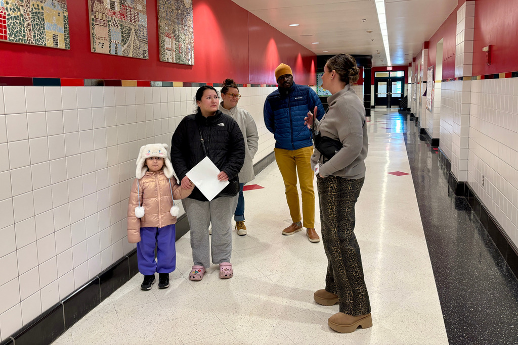A staff member walks a family through the school during an open house.