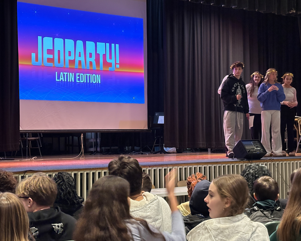 Doherty High School students stand on stage and give a presentation to a crowd of middle school students.