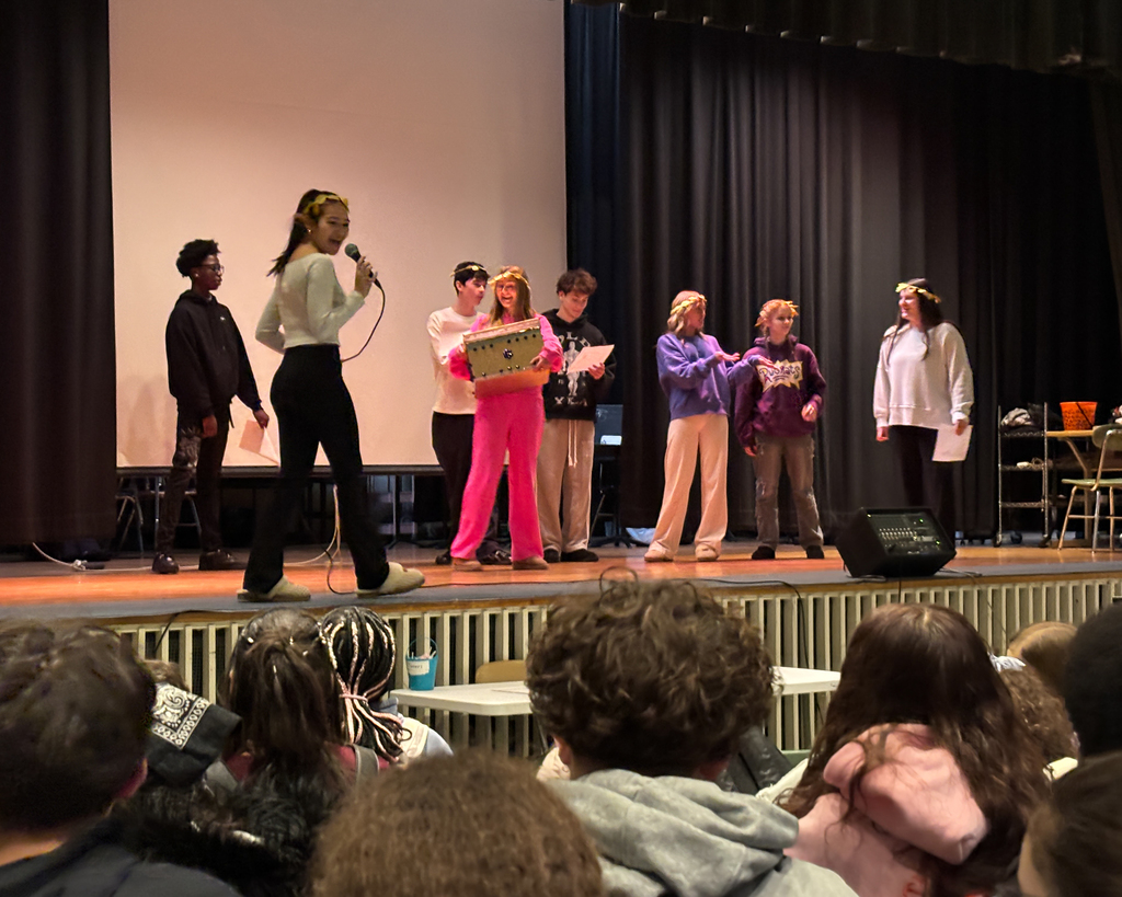 Doherty High School students stand on stage and give a presentation to a crowd of middle school students.